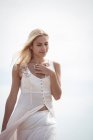 Schöne blonde Frau im weißen Kleid, die draußen spaziert — Stockfoto