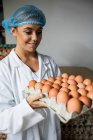 Portrait of female staff holding egg tray in factory — Stock Photo