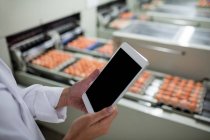 Abgeschnittenes Bild weiblicher Mitarbeiter mit digitalem Tablet neben dem Fließband in der Eierfabrik — Stockfoto