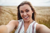 Камера с точки зрения улыбающейся женщины, стоящей на пшеничном поле в солнечный день — стоковое фото