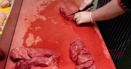 Руки м'ясника рубають червоне м'ясо в м'ясному магазині — стокове фото