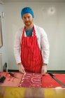 Macellaio in piedi con un vassoio di bistecche in macelleria — Foto stock