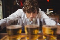 Bartender lining whisky shot glasses on bar counter at bar — Stock Photo