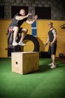 Два спортсмена практикуют на деревянной коробке в фитнес-студии — стоковое фото