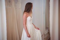 Жінка намагається на весільній сукні в магазині в студії — стокове фото