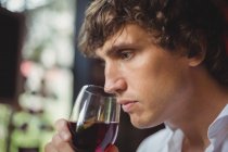 Uomo che beve un bicchiere di vino rosso al bar — Foto stock