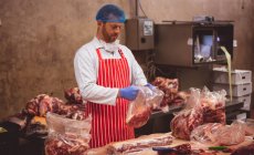 Boucher emballant la viande rouge dans la salle d'entreposage à la boucherie — Photo de stock
