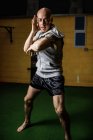 Beau boxeur thaïlandais fort pratiquant la boxe dans la salle de gym — Photo de stock