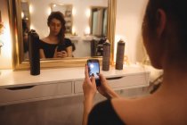 Женщина использует мобильный телефон в салоне красоты — стоковое фото