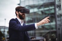 Businessman using virtual reality headset outside office — Stock Photo