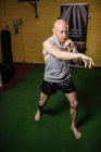 Vue grand angle du beau boxeur thaïlandais pratiquant la boxe dans la salle de gym — Photo de stock