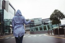 Vue arrière de la femme debout dans la rue pendant la saison des pluies — Photo de stock