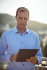 Porträt eines Geschäftsmannes, der ein digitales Tablet benutzt, während er im Büro auf dem Balkon steht — Stockfoto