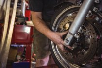 Механик осматривает мотоциклетный диск в мастерской — стоковое фото