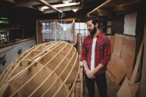 Man looking at wooden frame of boat in boatyard — Stock Photo
