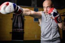 Selective focus of handsome Thai boxer practicing boxing in gym — Stock Photo