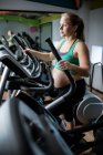 Mujer embarazada haciendo ejercicio en la cinta en el gimnasio - foto de stock