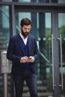 Businessman using mobile phone outside office — Stock Photo