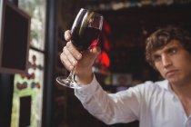 Бармен смотрит на бокал красного вина за барной стойкой — стоковое фото