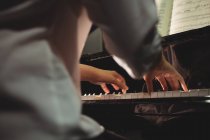 Sección media de alumna tocando el piano en un estudio - foto de stock
