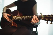 A meio da seção da mulher tocando guitarra na escola de música — Fotografia de Stock