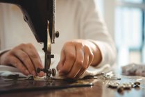 Sección media de costura de costura femenina en la máquina de coser en el estudio - foto de stock
