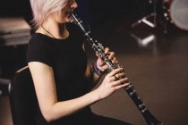 Female student playing clarinet in a studio — Stock Photo