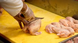 Руки мясника рубят курицу на рабочем столе в мясной лавке — стоковое фото