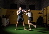 Повна довжина двох тайських боксерів, які практикують в спортзалі — стокове фото