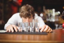 Bartender preparando e forro copos de tiro para bebidas alcoólicas no balcão do bar no bar — Fotografia de Stock