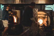 Команда стеклодувов нагревательного стекла в печи на стекольном заводе — стоковое фото