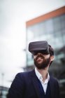Businessman using virtual reality headset outside office — Stock Photo