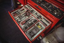 Herramientas de automóvil dispuestas en caja de herramientas en el taller - foto de stock