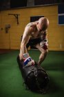 Boxeador practicando boxeo con saco de boxeo en gimnasio - foto de stock