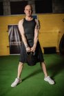 Schöner Sportler, der im Fitnessstudio Gewicht hebt und in die Kamera schaut — Stockfoto