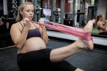 Femme enceinte faisant de l'exercice avec une bande de résistance au gymnase — Photo de stock
