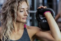 Beautiful woman lifting kettlebell at gym — Stock Photo