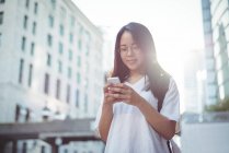 Молода жінка використовує мобільний телефон на вулиці — стокове фото