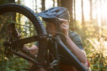 Чоловік-велосипедист ремонтує свій велосипед у лісі в сонячний день — стокове фото