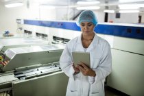 Женщины-сотрудники используют цифровые планшеты рядом с производственной линией на яйцефабрике — стоковое фото