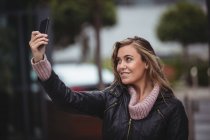 Beautiful woman taking selfie by smartphone on street — Stock Photo
