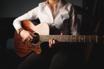 Mi-section de la femme jouant une guitare à l'école de musique — Photo de stock