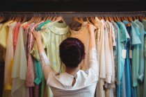 Жінка вибирає одяг з вішалок в магазині — стокове фото