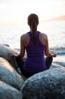 Vista posteriore della donna che esegue yoga sulla roccia nella giornata di sole — Foto stock
