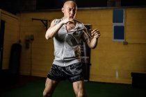 Handsome athletic Thai boxer practicing boxing in gym — Stock Photo