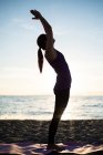 Vista lateral de la Mujer realizando yoga en la playa en un día soleado - foto de stock