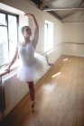 Вид спереди на Балерину, практикующую балетный танец в баре в студии — стоковое фото