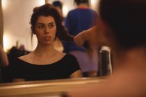 Reflexão de uma mulher bonita no espelho styling seu cabelo no salão — Fotografia de Stock