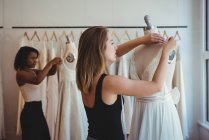 Diseñadoras de moda ajustando el vestido en un maniquí en el estudio - foto de stock