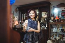 Retrato de una mujer sonriente comprando antigüedades en una tienda de antigüedades - foto de stock